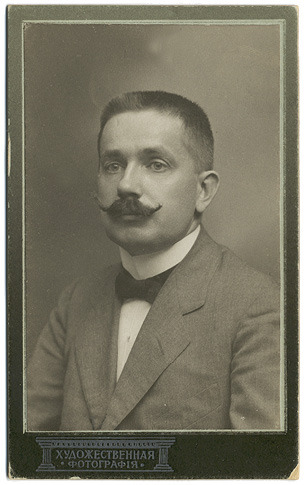 Jānis Endzelīns in Kharkiv (~1920) (Latvian National Museum of Literature and Music, No. RMTM 246629). Portrait of an approximately 40-year-old man: short hair, mustache, wearing a light-colored jacket, a white shirt, and a dark bow-tie.