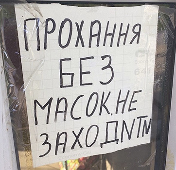 Фото 3. На входной двери магазина на стекле приклеен лист бумаги с надписью на украинском с ошибками: «ПРОХАННЯ БЕЗ МАСОК НЕ ЗАХОДИТИ» (в слове «ЗАХОДИТИ» дважды используется латинская буква “N” вместо кириллической «И»). Перевод этого текстового фрагмента на русский: «Просьба без масок не заходить».