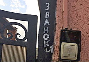 Фото 1. На чёрной металлической части ворот у входа в частный дом белой краской вертикально написано русское слово «ЗВОНОК» с ошибкой (здесь вместо первой буквы «О» используется «А») и ниже указан номер 1, справа на розовой стене установлен другой дверной звонок с номером 2.