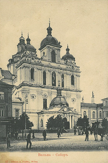 A historic baroque-style cathedral with multiple domes stands in a town square where people and a horse-drawn carriage are present.

Description generated by AI